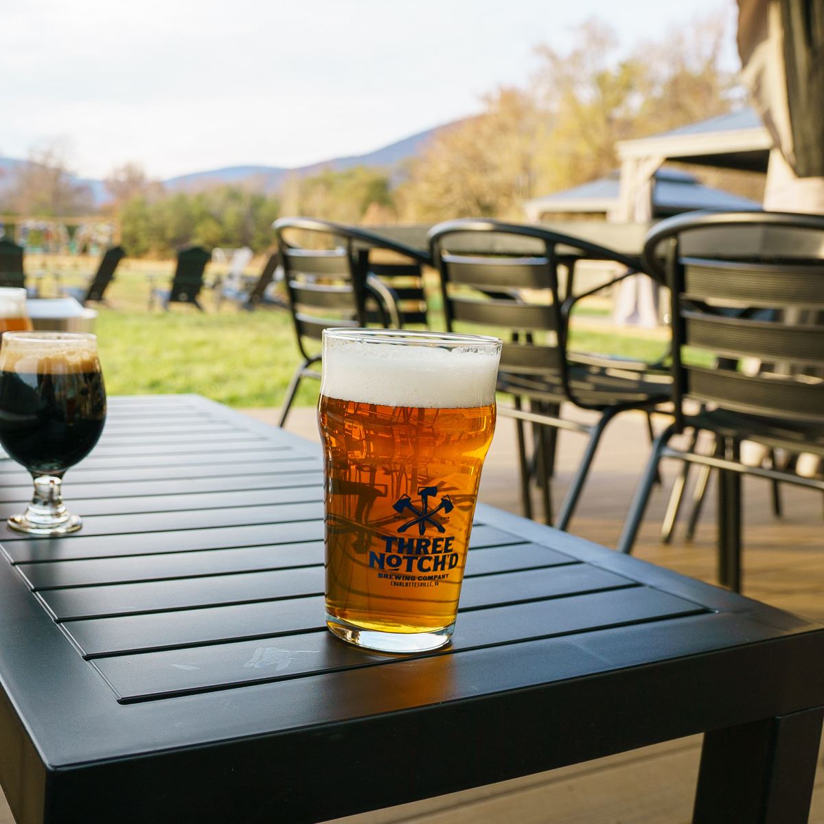 Two pints on a patio table with the mountains behind